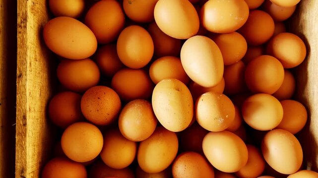 Fresh brown chicken eggs fill a rustic wooden crate at a local market.