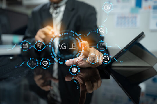 Agile development methodology concept. Business hand using laptop computer and tablet with virtual screen agile icon on modern office digital technology concept.