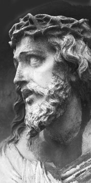 Black and white close-up of a stone statue of Jesus Christ wearing the crown of thorns, looking toward heaven in prayer on Golgotha, symbolizing sacrifice, faith, redemption, hope, and devotion.