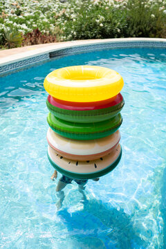 Child in pool under a pile of floats in summer time