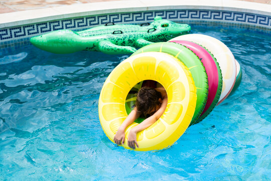 Child in pool inside a pile of floats in summer time