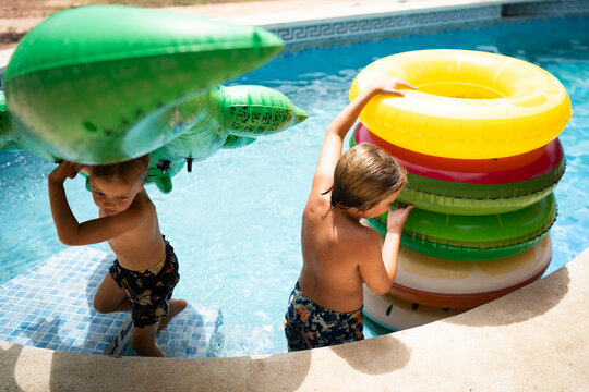 Young children stacking up floats in pool during summer