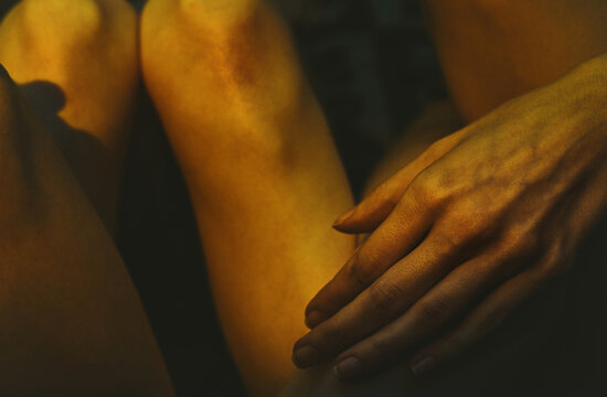 Close up of hand resting on leg in golden light