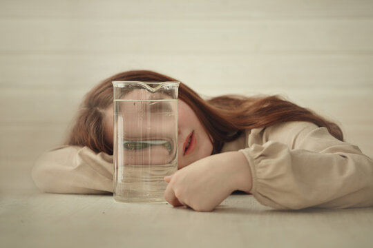 A young girl with long red hair is lying on a light wooden table