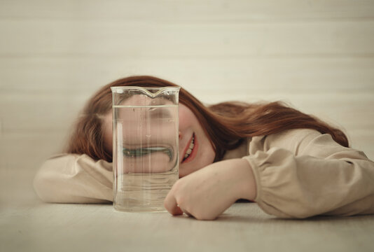 A young girl with long red hair is lying on a light wooden table