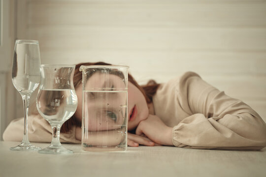 A young girl with long red hair is lying on a light wooden table