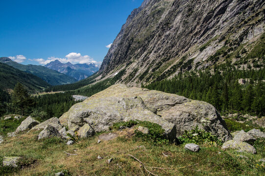 Hiking through a mountain valley with large rocks and trees under a