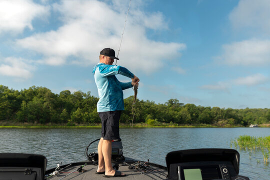 Fisherman unhooking a small bass on a lake