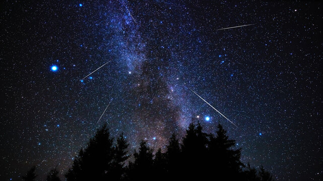 Milky way stars and constellations with landscape silhouettes photographed from a dark countryside location.