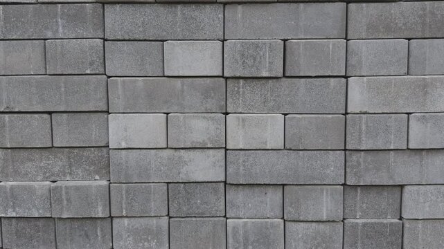 Paving block tiles and slabs moving upward from stacked pile for sidewalk pavement construction in pedestrian zone, ready for installation.