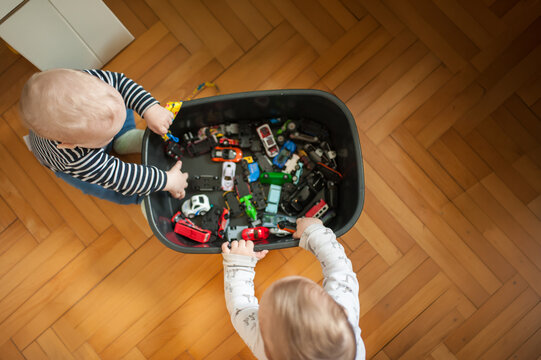 Children play with colorful toy cars on a wooden floor in the afternoon