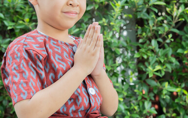 Side view close-up of happy little Thai boy doing Sawasdee greeting © Kunlathida