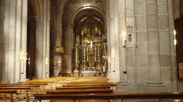 The camera moves laterally across the wide nave of a medieval cathedral revealing rows of wooden pews.