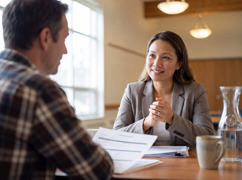 Two people having a meeting at a table with documents coffee mug and water carafe