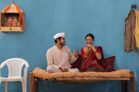 Maharashtrian couple having tea while sitting on cot at home