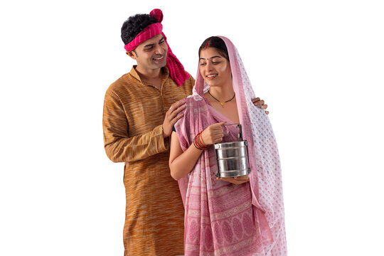 Portrait of happy couple standing with lunch box against white background
