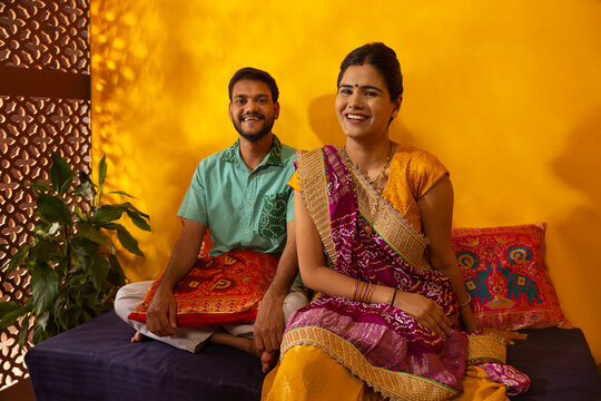 Portrait of smiling Gujrati couple sitting on deewan at home