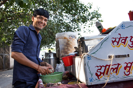 Portrait of a smiling male vendor chopping onion at his roadside stall