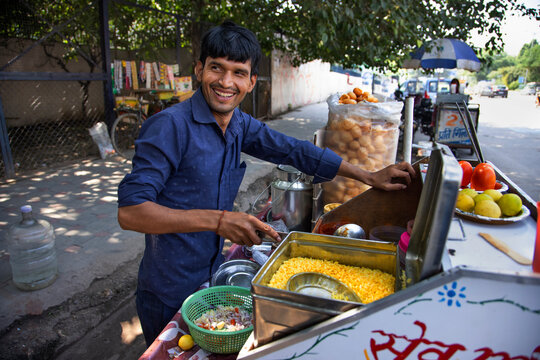 Portrait of a happy street vendor preparing ingredients at his stall