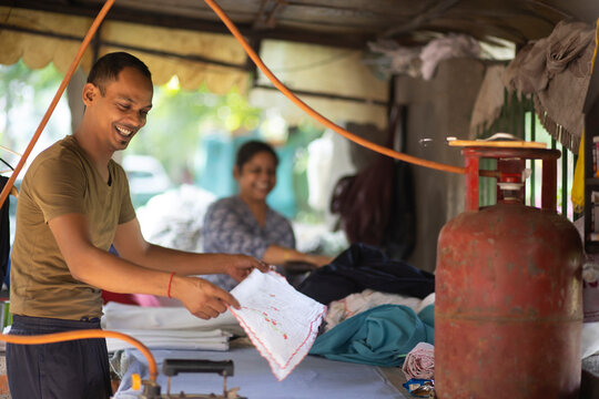 Smiling Man,dhobi ironing clothing outside using a gas cylinder