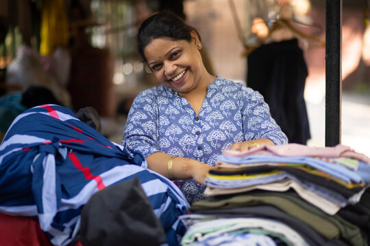 A portrait of a woman  folding clothes after ironing them for delivery