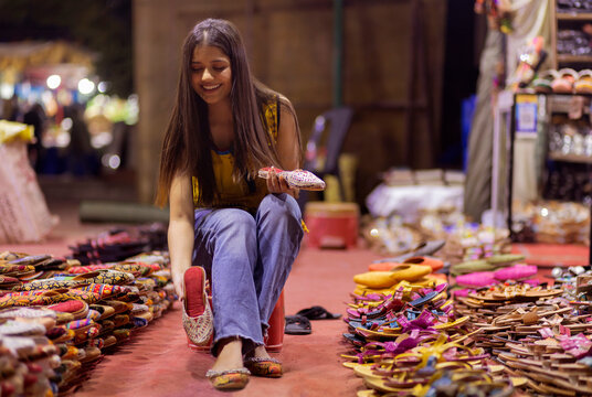 Gril selecting from two pairs of sandals in street shop
