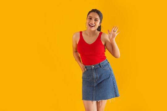 Portrait of a smiling teenage girl gesturing while standing against yellow background