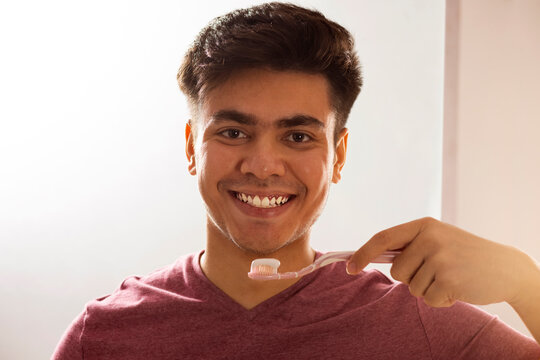 Close-up portrait of a smiling man brushing his teeth