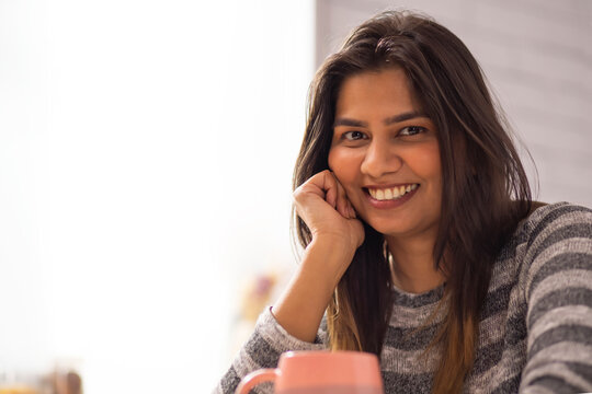 Close-up portrait of smiling woman drinking coffee at home