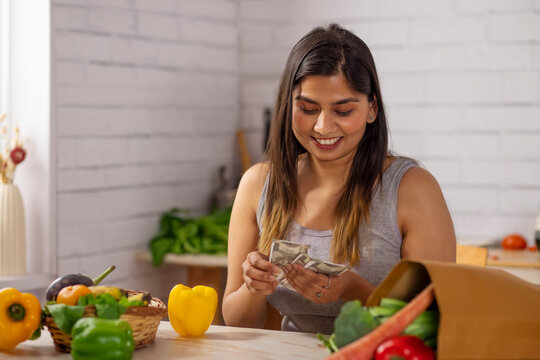 Woman counting money in kitchen after shopping