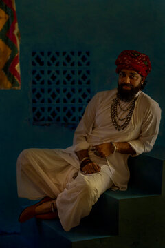 Portrait of smiling Rajasthani man leaning on stair at home
