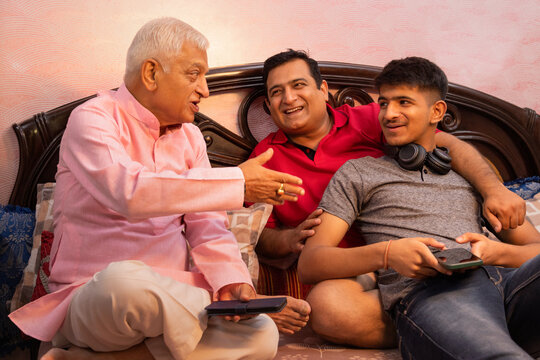 Multi generation Indian family sitting on bed in bedroom