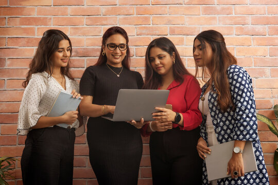 Group of businesswomen discussing project on laptop at office workstation