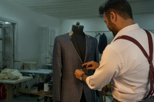 A bespoke tailor checking measurements on a dress form 