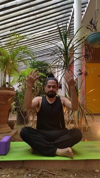 Man wearing black sportswear on lotus pose teaching yoga breathing on green mat at the garden. instructor blogger filming yoga tips at noon. Vlogger live streaming. User-generated content UGC