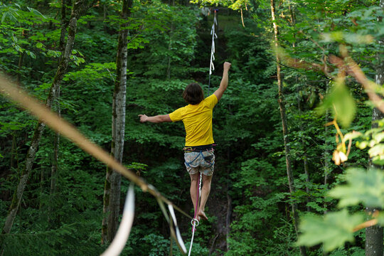 Slacklining highline walking balancing forest athlete extreme sport risk challenge motivation focus yellow shirt