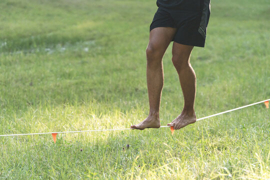 Barefoot feet balancing on a thin line over green grass, representing mindfulness, steady steps forward, and choosing an unconventional path in life or career