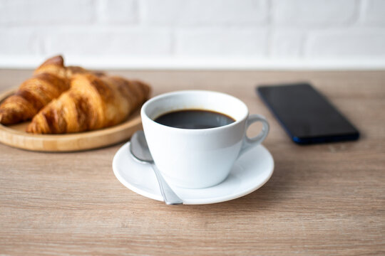 Buttered whole wheat toast with black coffee and smartphone on wooden table