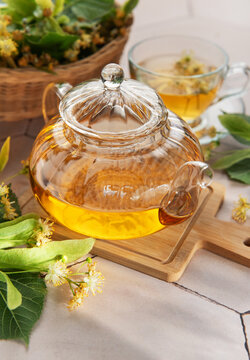 Linden tea brewing in glass teapot with lime blossom