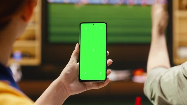 Chroma key smartphone used by football fans at home pleased by goal scored during match with cheerful soccer supporters having fun during live game broadcast, using isolated screen mobile phone.