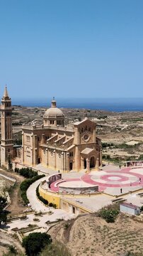 Vertical drone video showcasing Ta' Pinu National Shrine in Gharb, Malta, captured in bright sunlight with sweeping aerial footage for mobile and social media.