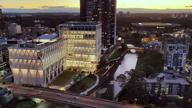 Powerhouse building illuminated at sunset in Parramatta city CBD on riverbank &ndash; aerial.