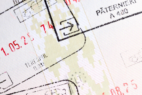 Close-up of official Schengen entry and exit ink stamps border checkpoints on patterned paper page of international travel passport document