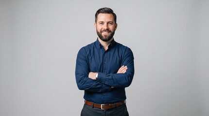Obraz premium Confident businessman standing with crossed arms against a solid grey studio background businessman confident