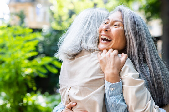 Mature women laughing while hugging female friend