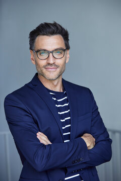 Portrait of stylish businessman with stubble wearing blue suit and glasses