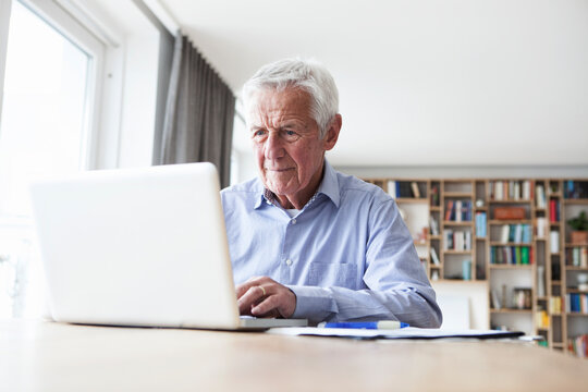 Portrait of senior man sitting at table using laptop