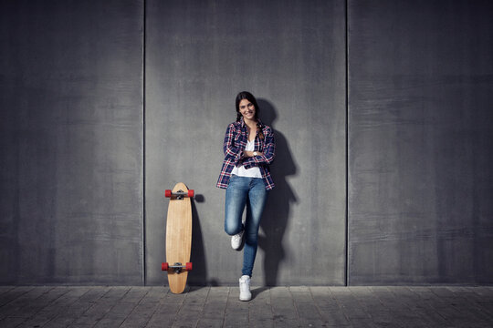 Young woman standing besides her longboard