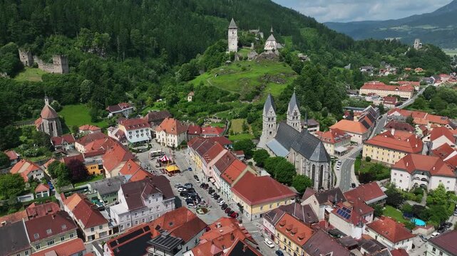 Summer drone footage showing medieval Friesach, old fortified walls, rooftops, towers, hills, serene atmosphere, warm daylight, gentle cinematic motion