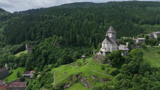 Summer drone footage showing medieval Friesach, old fortified walls, rooftops, towers, hills, serene atmosphere, warm daylight, gentle cinematic motion